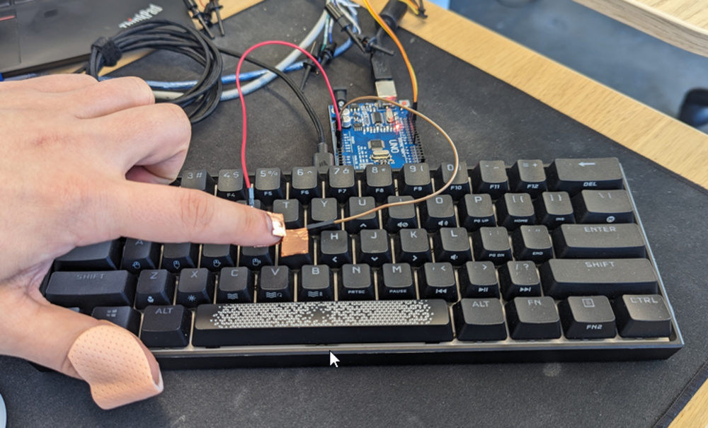 An image of a human finger testing key actuation on the Corsair K65 RGB MINI